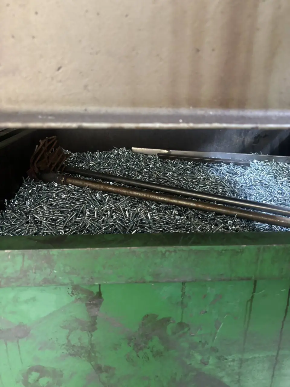 Steel bin full of rejected screws